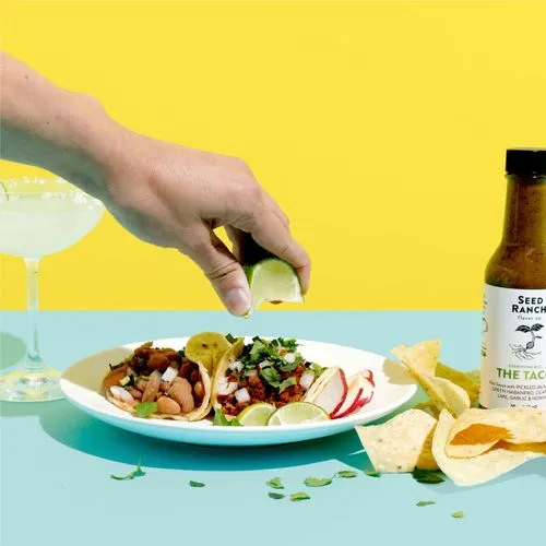 someone squeezing a lime over tacos