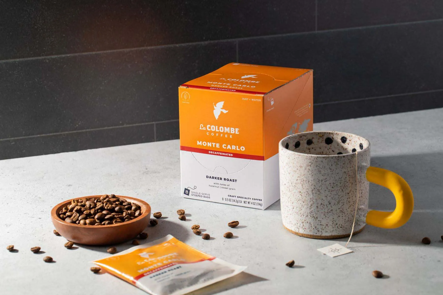 Amazon product photo of La Colombe Monte Carlo coffee box with cup and scattered coffee beans on countertop