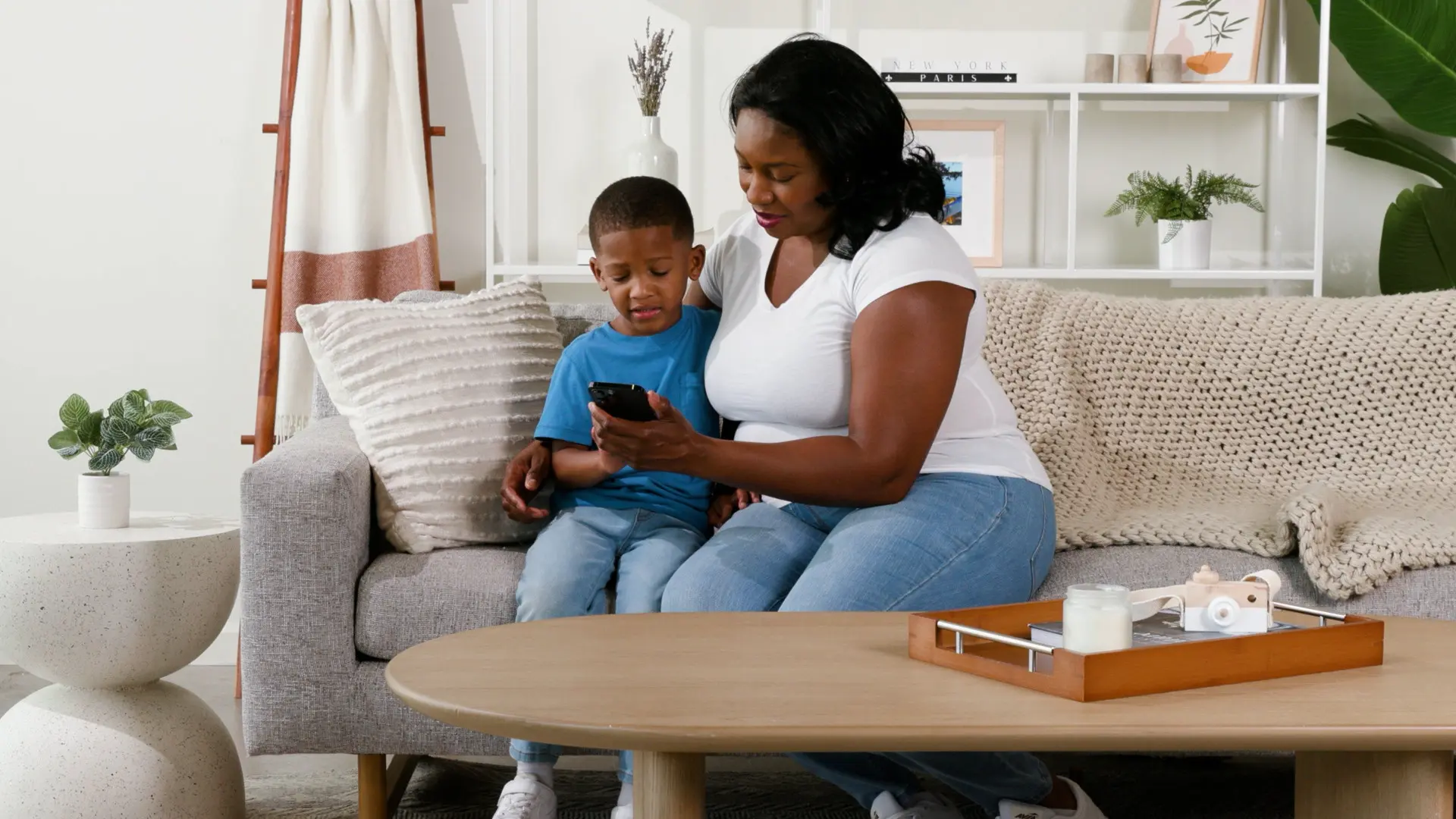 Mother showing child an app on her phone in the living room