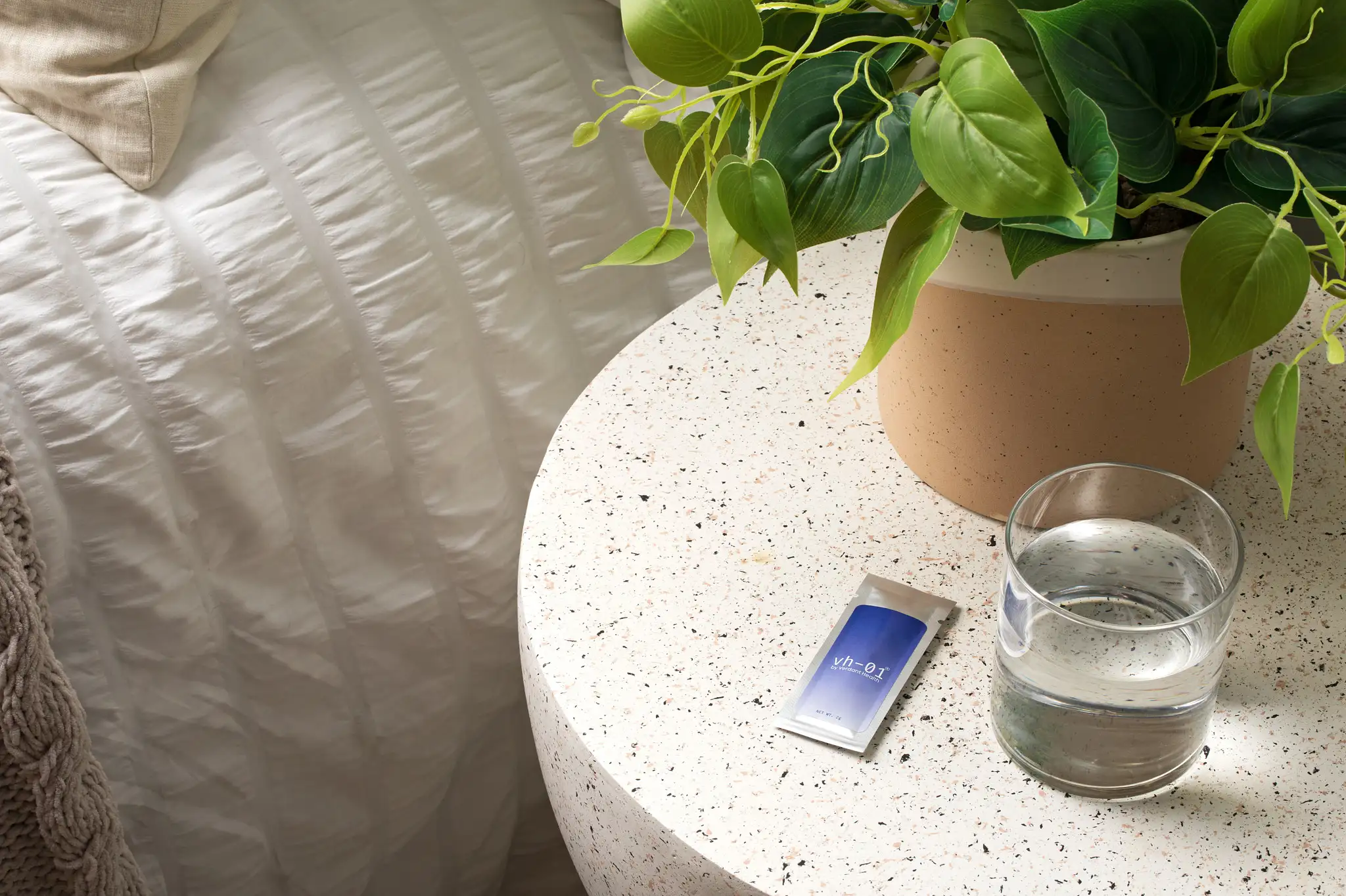 nightstand with a glass of water and a small health packet