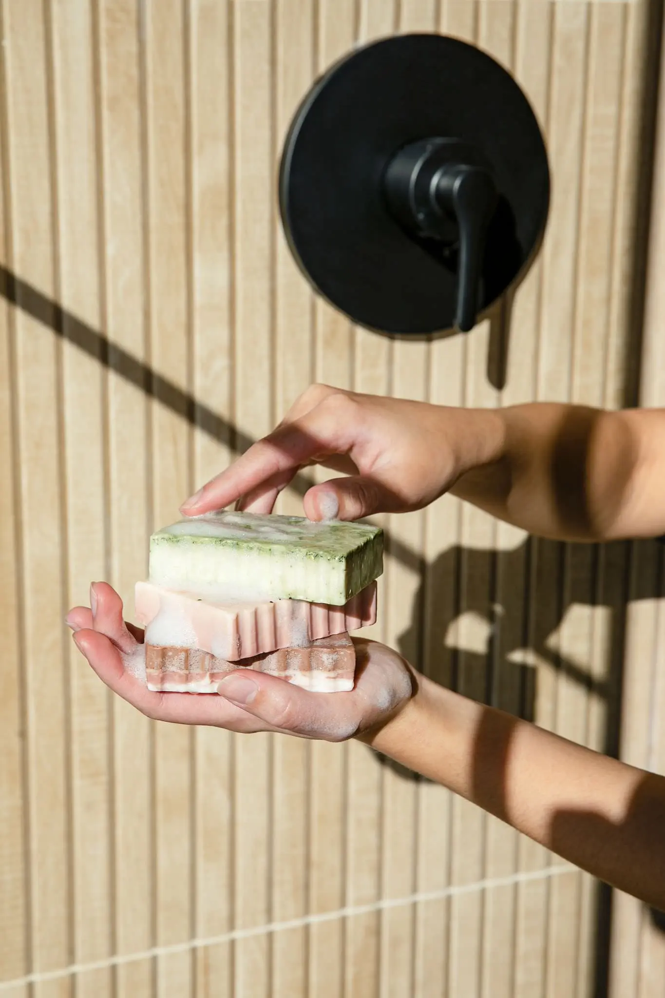 hands lathering up with a bar of soap in a shower