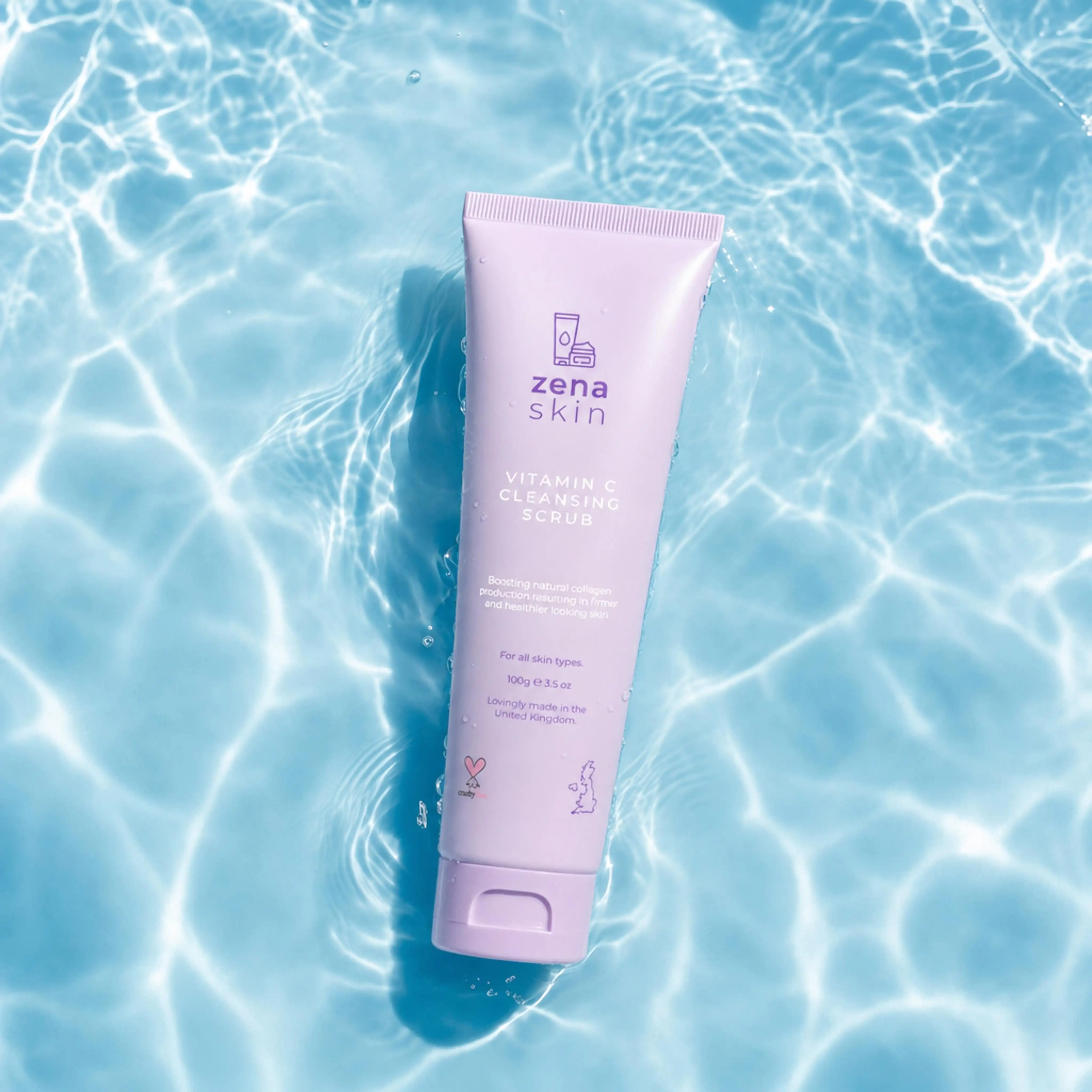 Zena Skin Vitamin C Cleansing Scrub tube floating in clear water with light reflections.