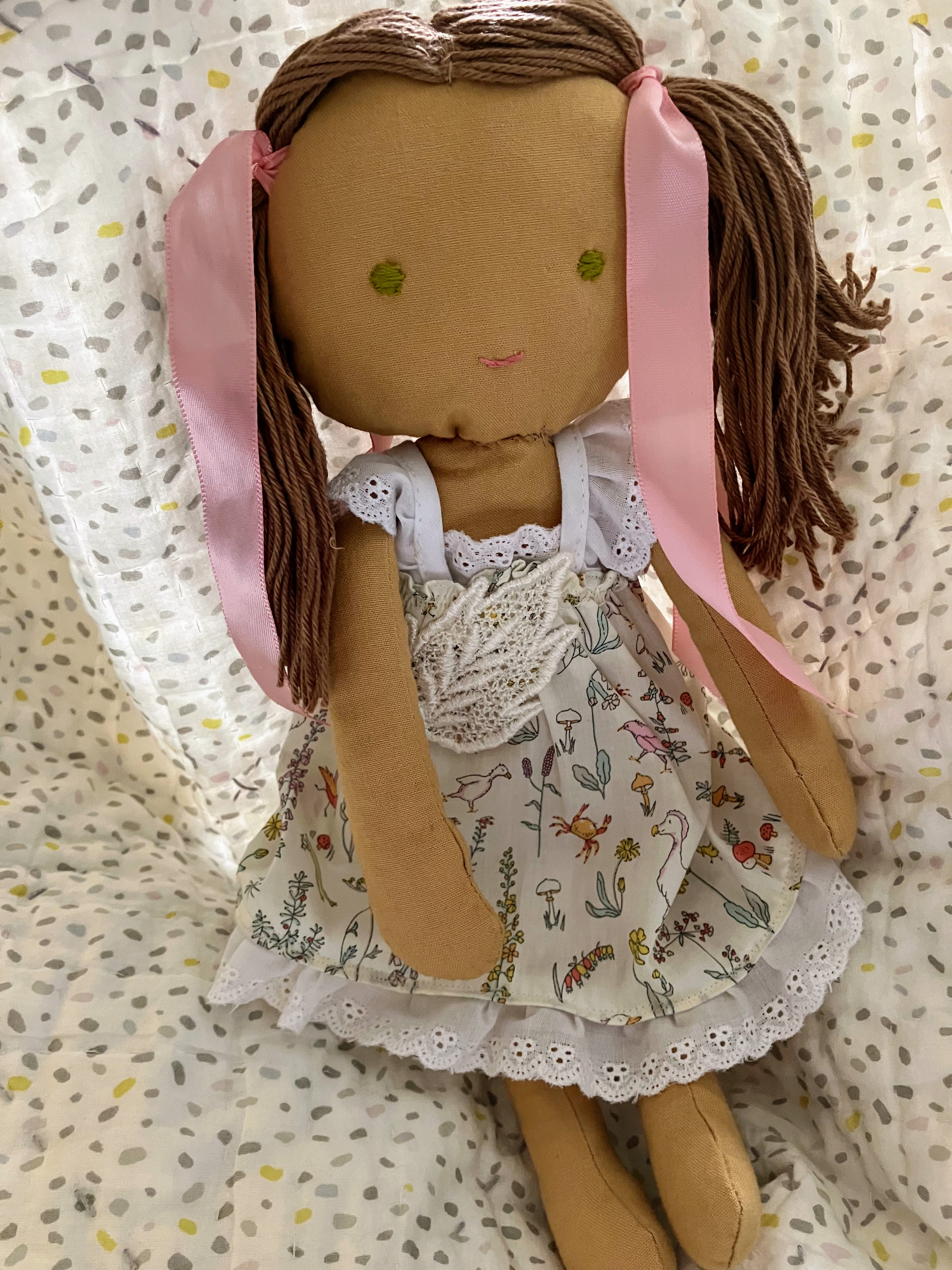 Girl doll wearing dress and pink ribbons around her hair for DIY customization project for hard of hearing children