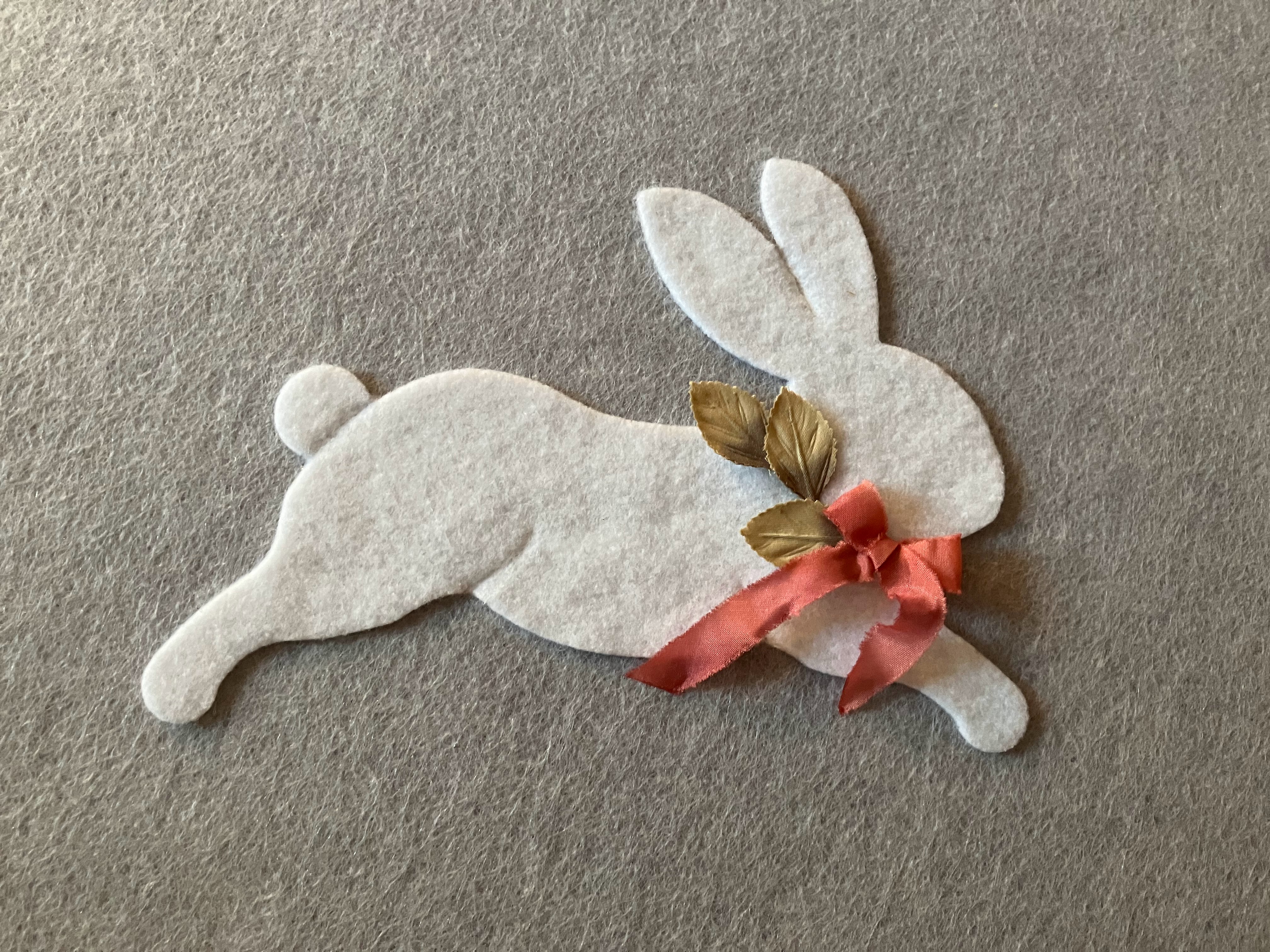 Felt rabbit decorated with a ribbon and leaf design, attached to an acoustic panel in a Montessori-style nursery for a hard of hearing child