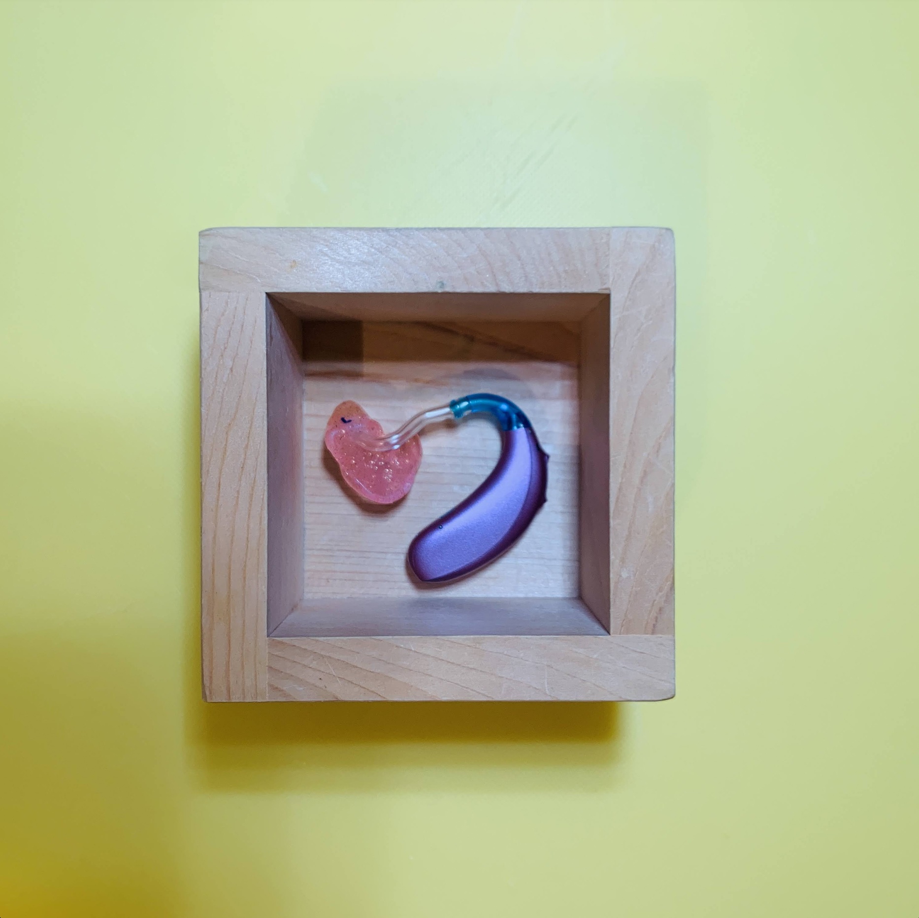 Small wood box containing a pediatric hearing aid