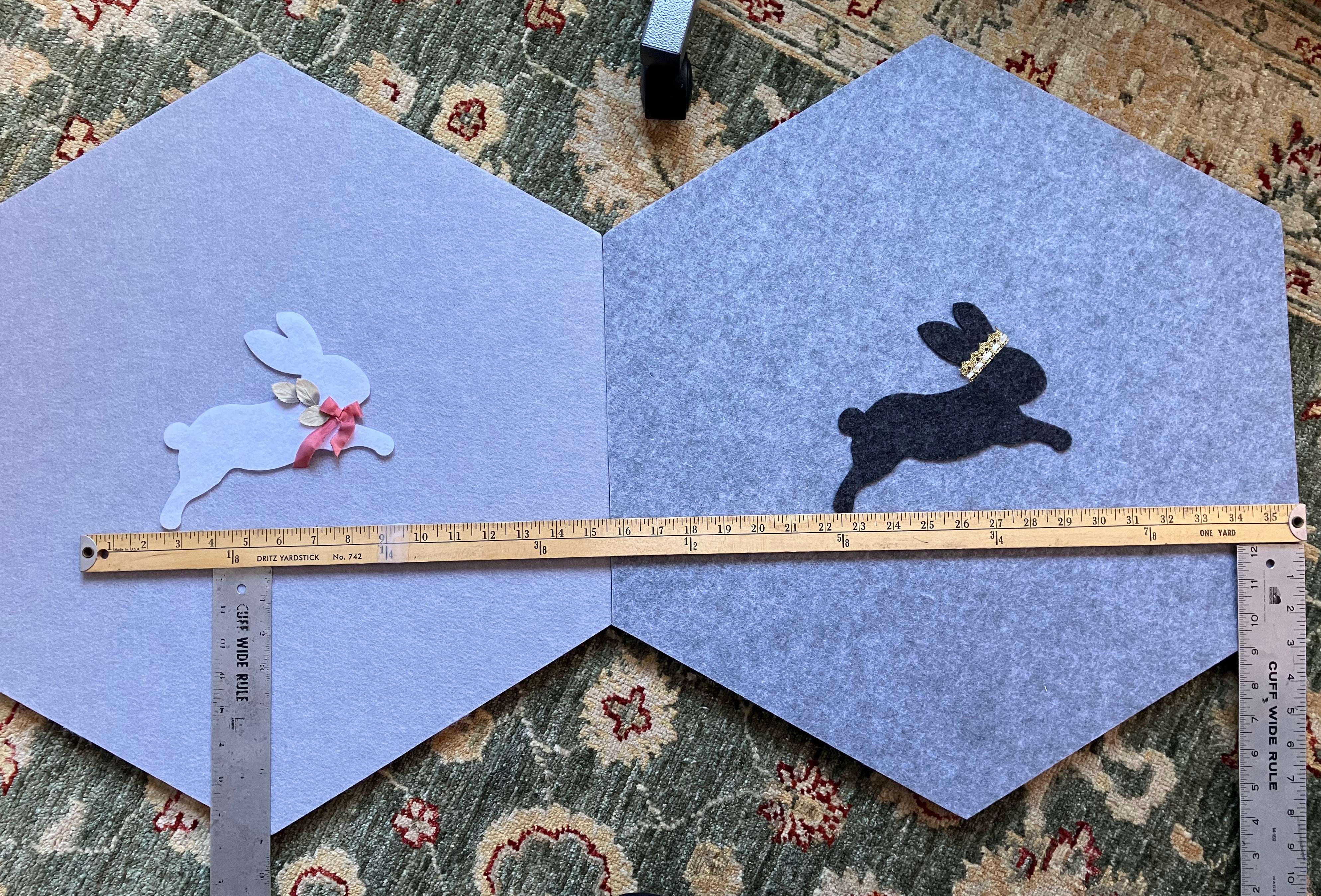 Light blue and gray hexagonal acoustic panels decorated with felt rabbits and measuring ruler, for child's room sound dampening