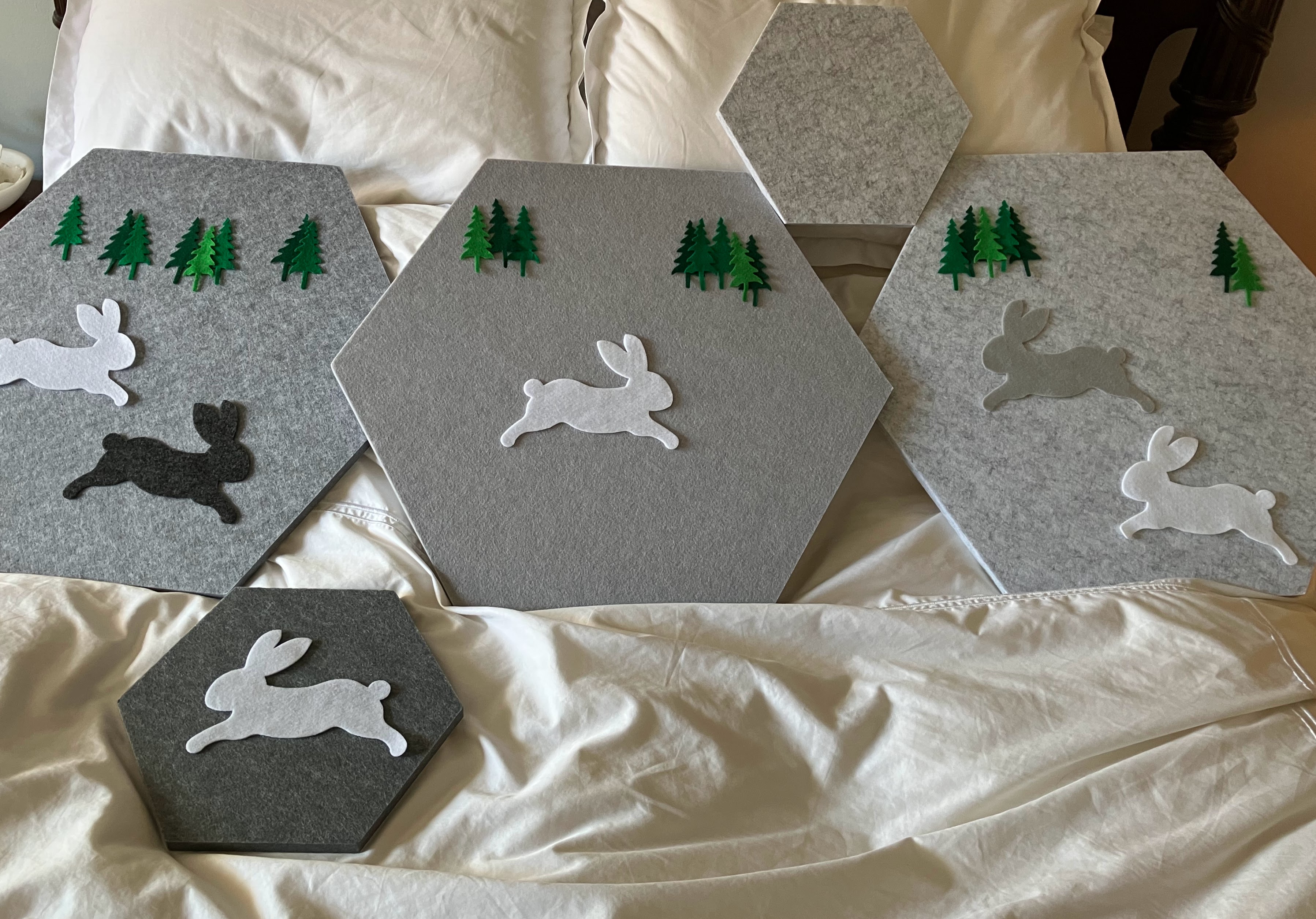 Gray hexagonal acoustic panels decorated with felt rabbits and trees for hard of hearing child's bedroom sound control