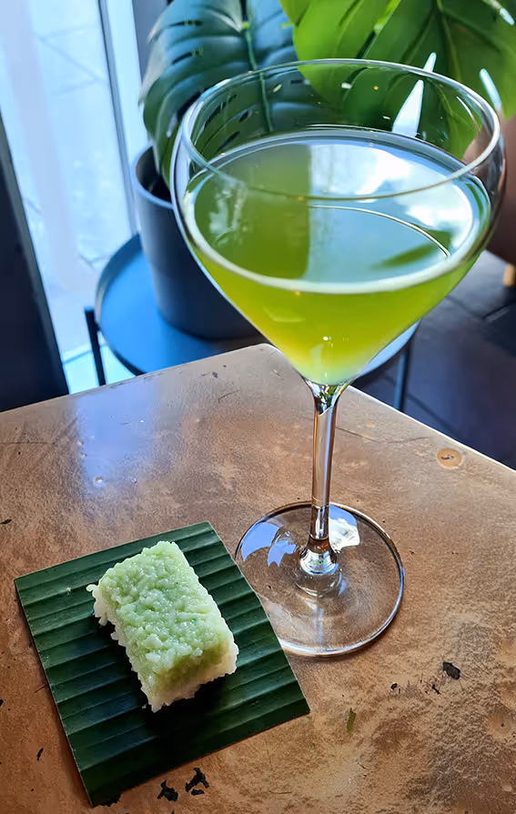 A green cocktail next to a piece of green cake