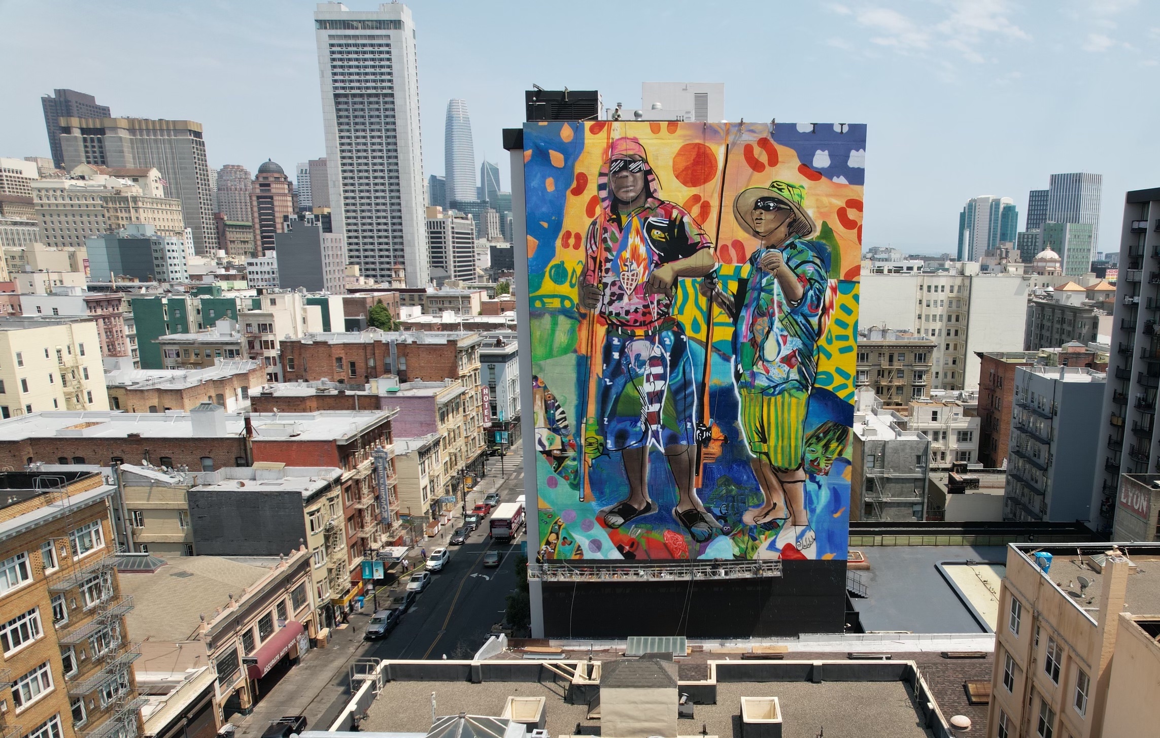 Aerial drone view of completed large-scale hand-painted public art mural on building exterior with San Francisco skyline