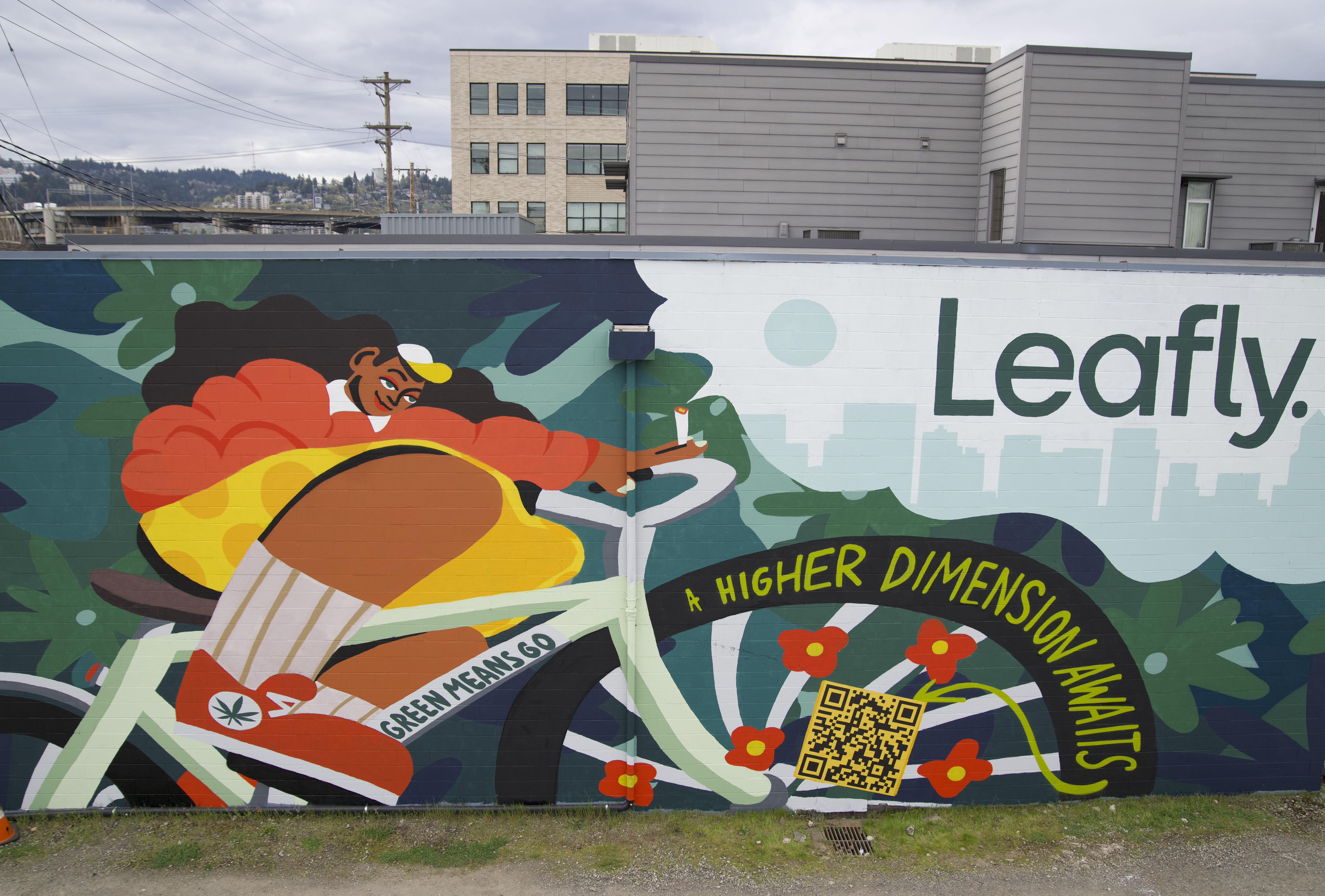 Completed Leafly hand painted mural advertisement with cyclist and QR code on building exterior in Portland Oregon