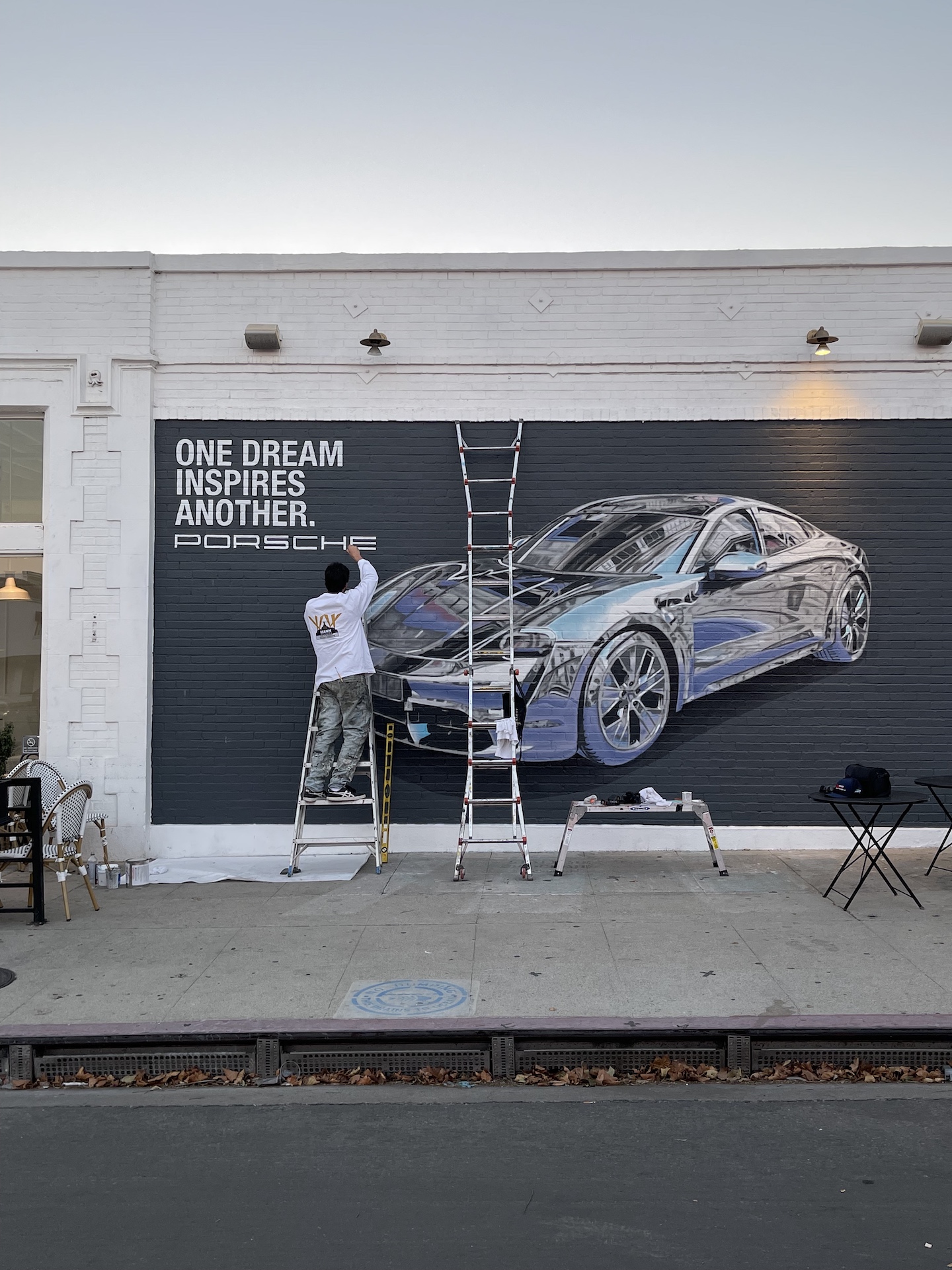 Hoist Media artist on ladder painting Porsche campaign lettering on brick wall on Melrose Avenue West Hollywood