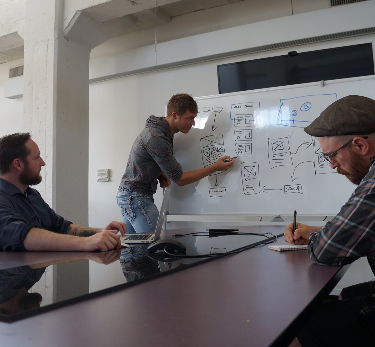 A VAULT designer walking the team through app wireframes on a whiteboard