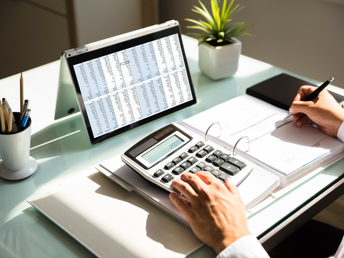 Business people reviewing documents while one holds a tablet at a glass desk.