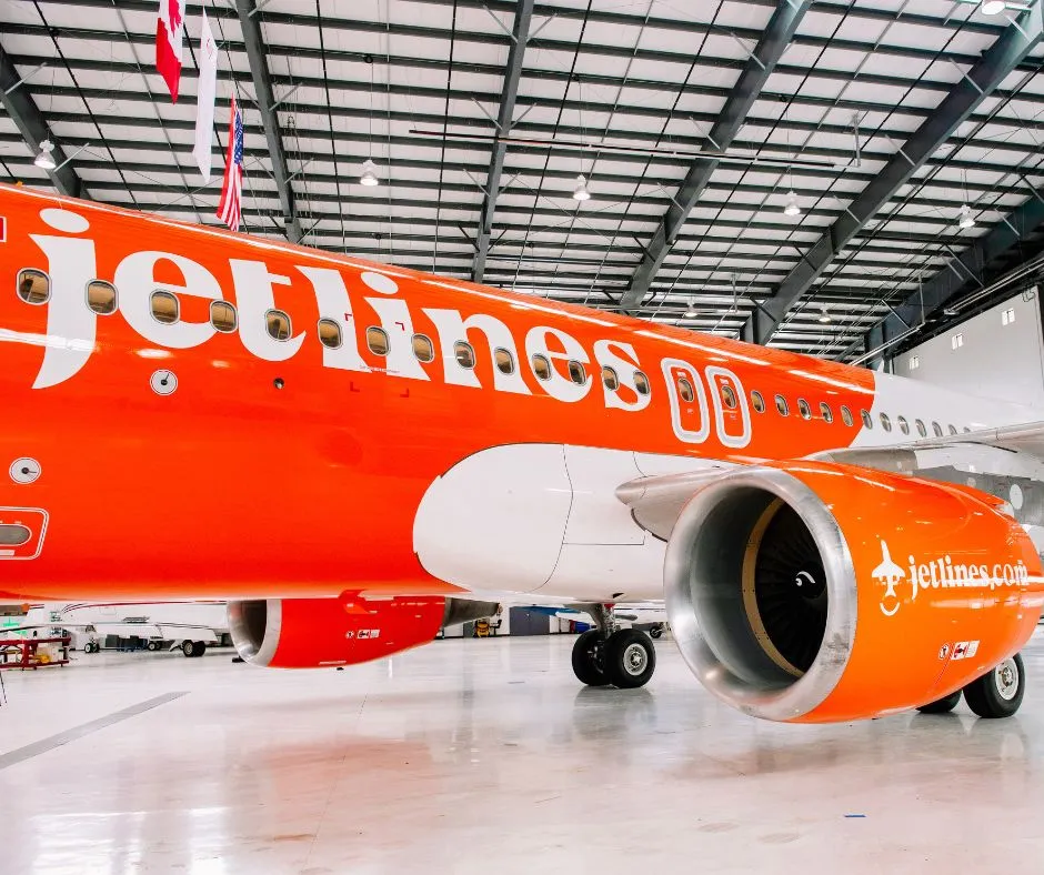 Jetlines logo on a orange aircraft inside a hangar 