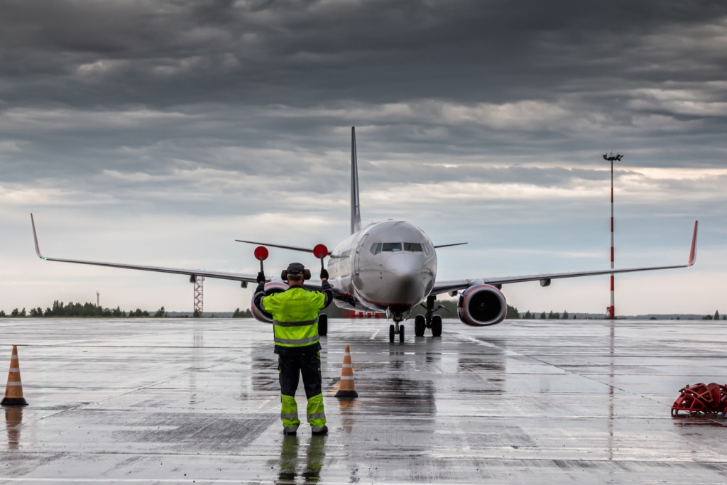 Aircraft marshalling at the aiport apron in rainy weather