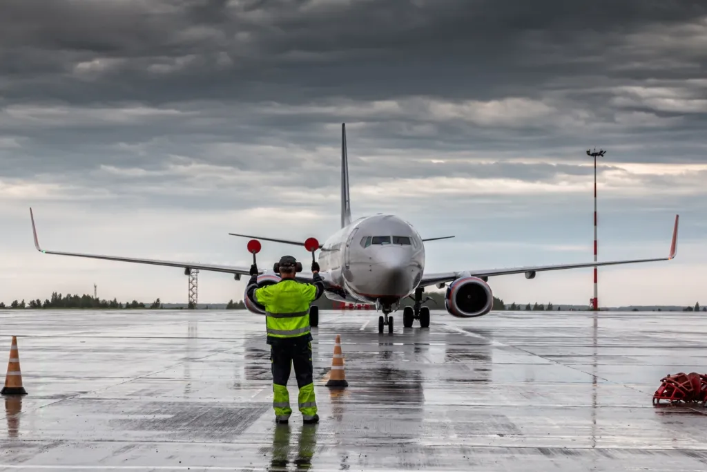 Aircraft marshalling at the aiport apron in rainy weather
