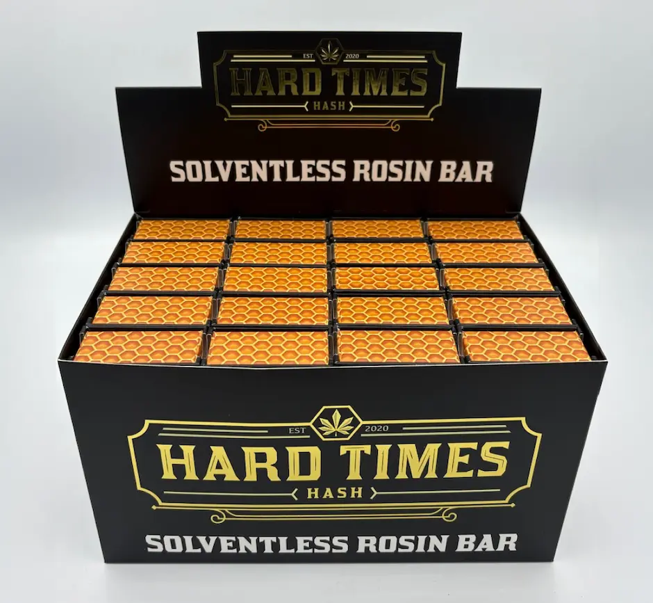 Display box with multiple solventless rosin bars in orange honeycomb-patterned packaging labeled Hard Times Hash.