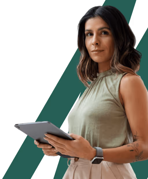 Woman with shoulder-length dark hair holding a tablet, wearing a sleeveless green top and beige pants, with a tattoo on her left forearm.
