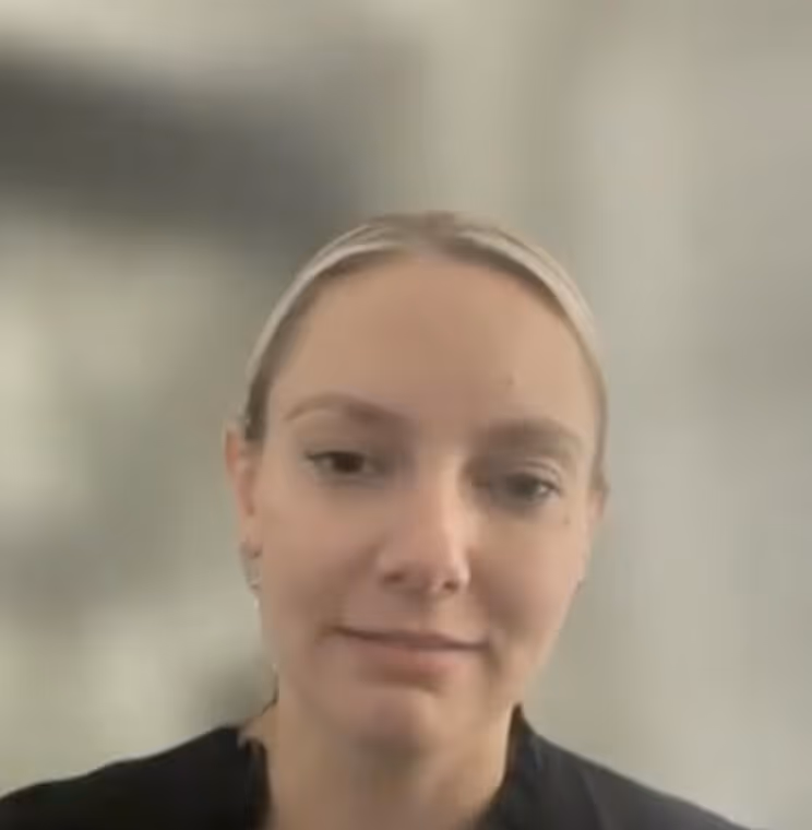 A women wearing glasses and a blue shirt is engaged in conversation.