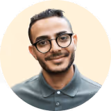Professional headshot of a smiling male employee wearing glasses and a grey polo shirt.