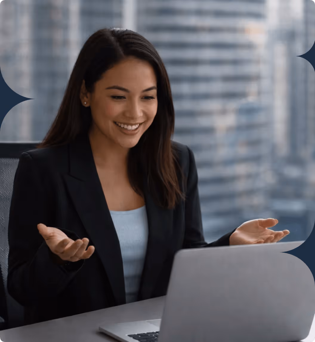 Professional woman gesturing during a video call on her laptop in a bright corporate office setting.