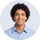 Smiling young man with curly hair wearing a light blue button-up shirt.