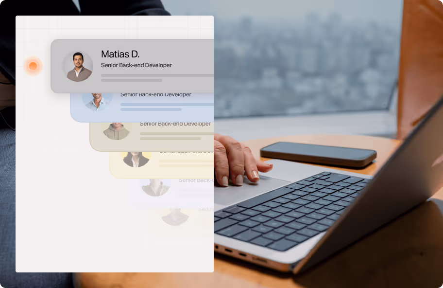 Hand typing on a laptop keyboard with a smartphone on the table and a layered team profile interface overlay.