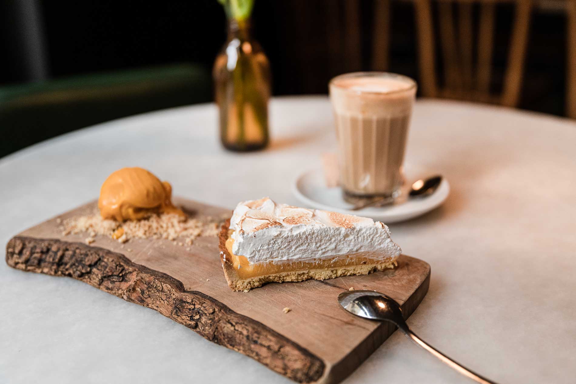 Merienda de trozo de lemon pie con helado de mango y un café con leche.