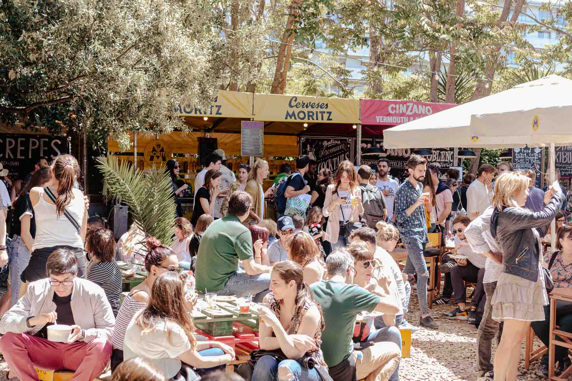Grupos de gente bebiendo y comiendo en la zona de restauración del Palo Market Fest de Poblenou en Barcelona.