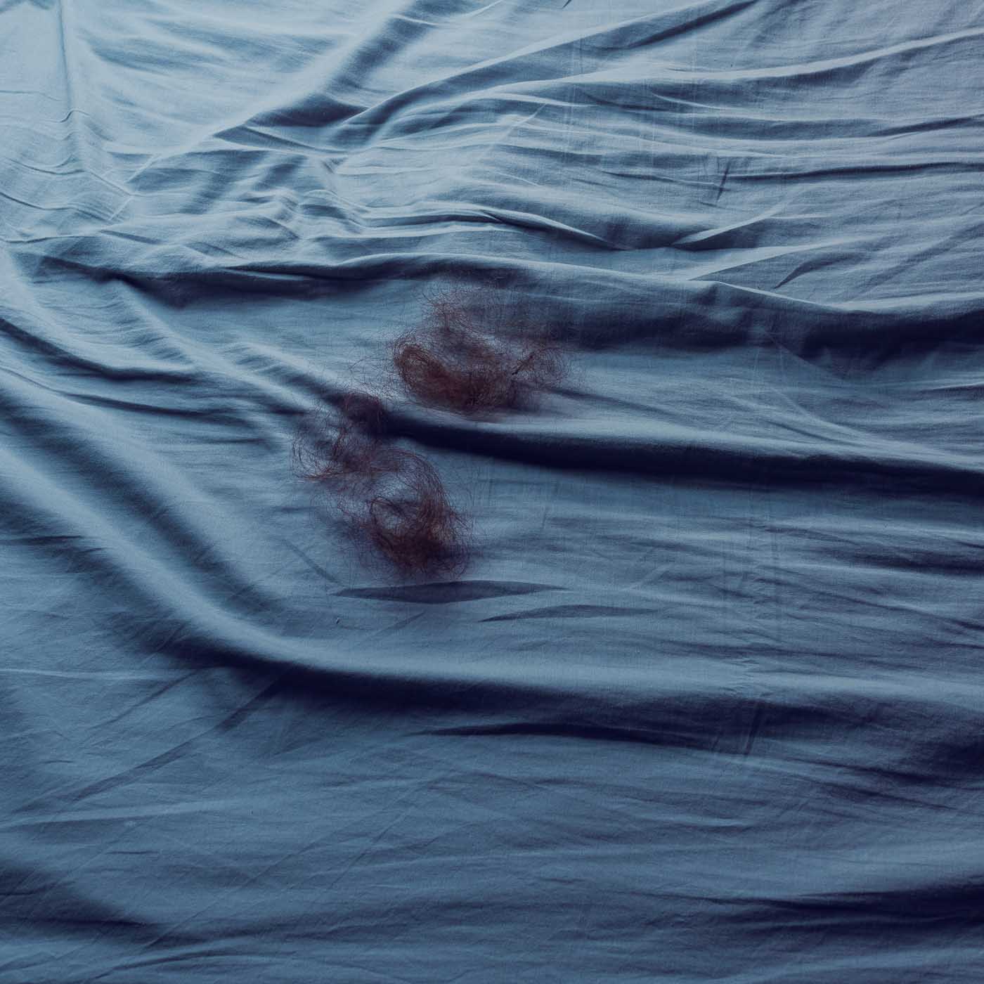 Imagen del díptico Tacto del proyecto Inconsciente de Elisa Blaz. Muestra una cama vacía en la que hay restos de cabello.