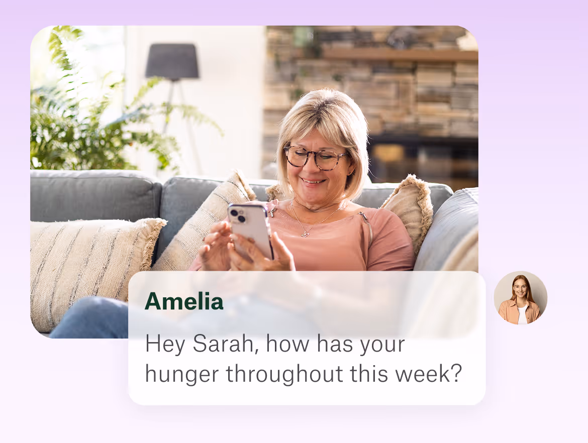 Smiling middle-aged woman wearing glasses lounging on a couch, looking at her phone with a message overlay from Amelia asking about hunger throughout the week.