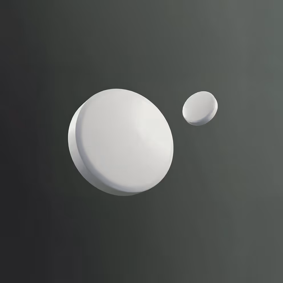 Close-up of two white round tablets on a dark surface, one larger and one smaller.