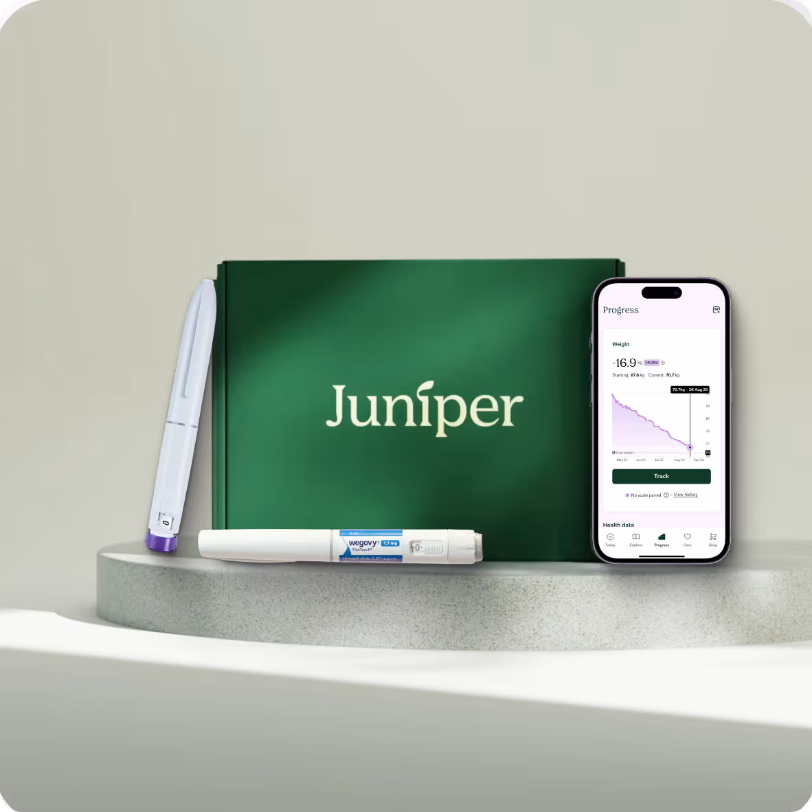 Juniper medication kit with two injection pens and a smartphone showing weight loss progress chart.