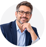 Smiling man with dark hair and glasses wearing a navy blazer and light blue shirt, resting his chin on his hand.