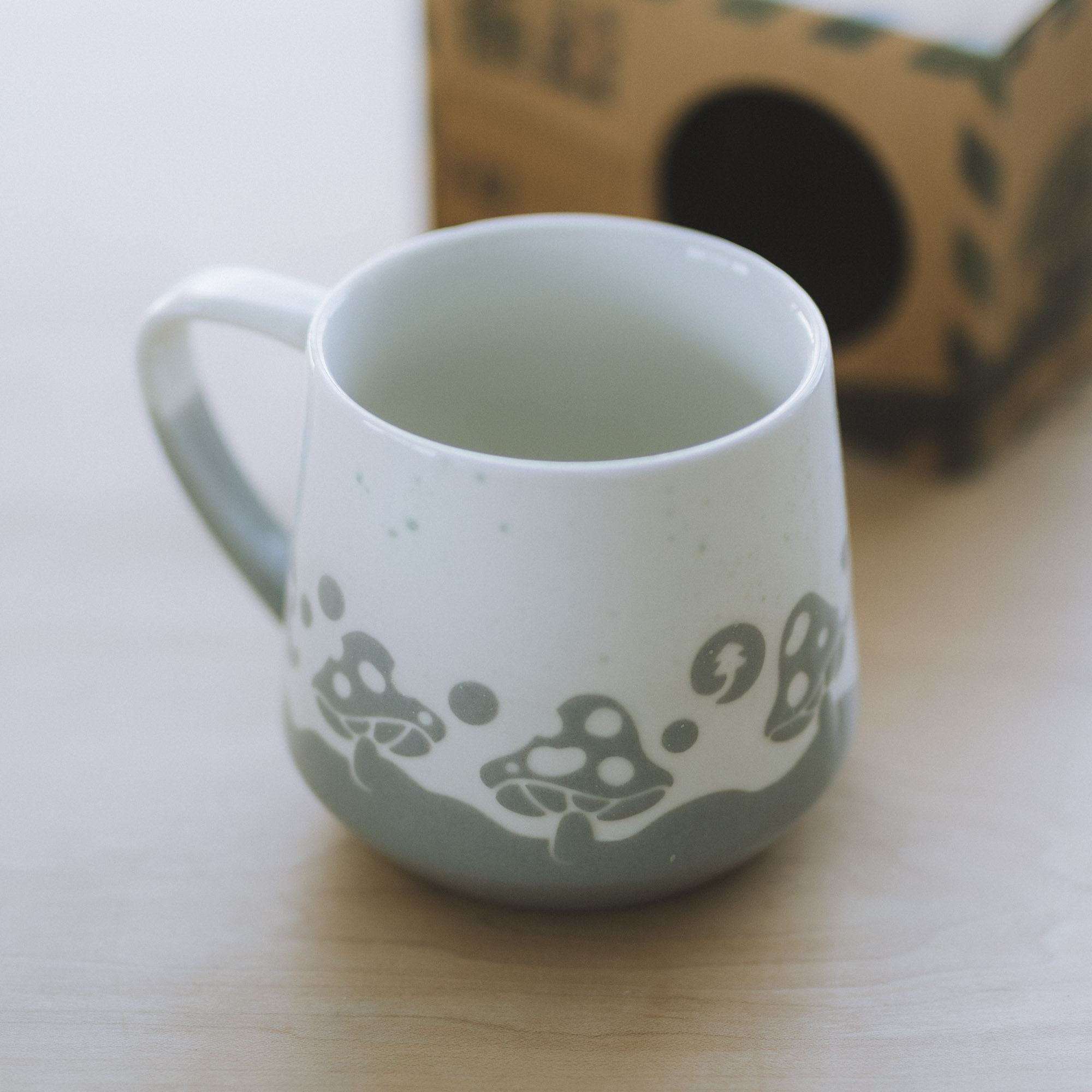 A speckled ceramic mug with a mushroom design along the bottom.