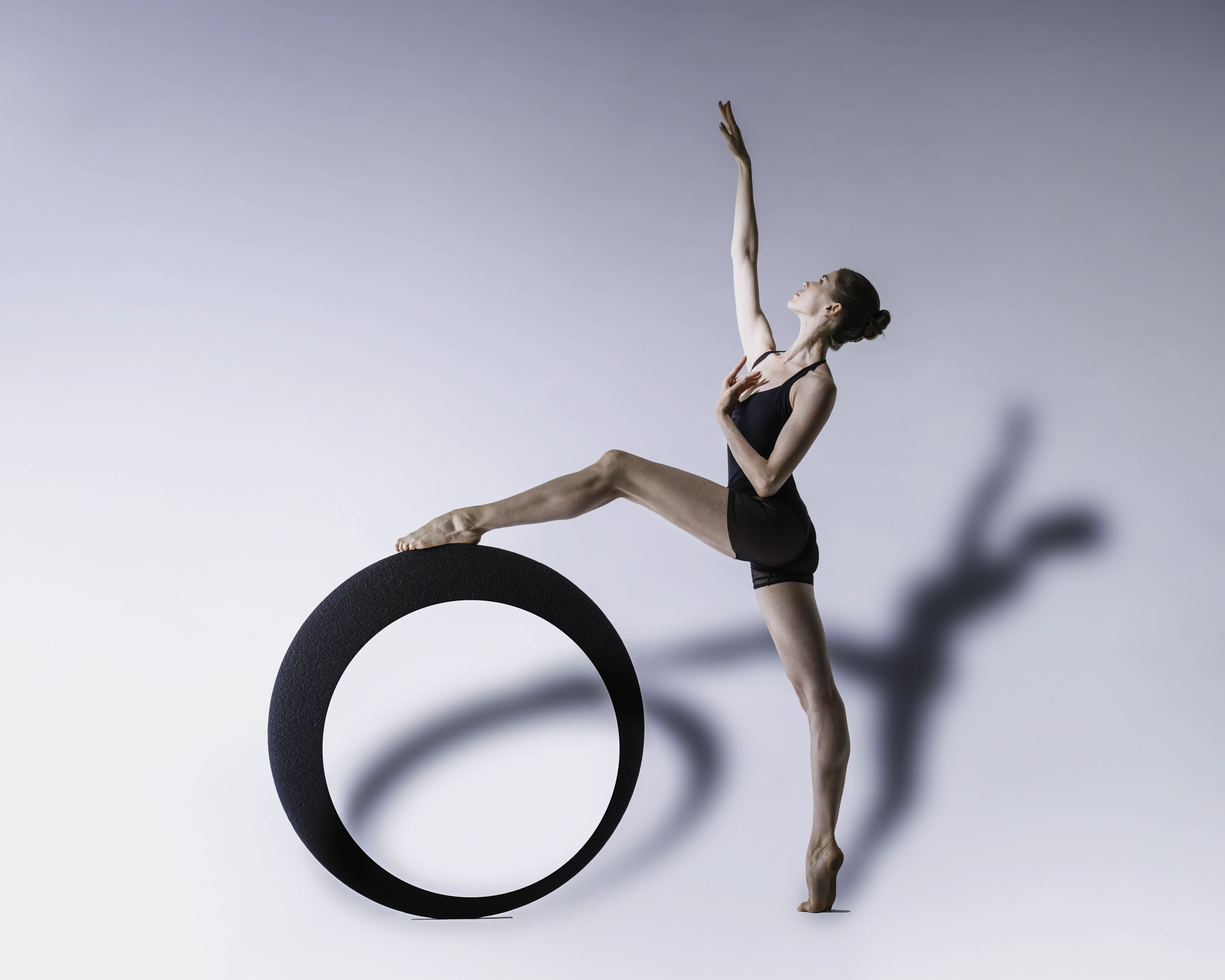 Ballerina Daria Stratovych in einer eleganten Pose neben einem schwarzen Ring mit markantem Schatten