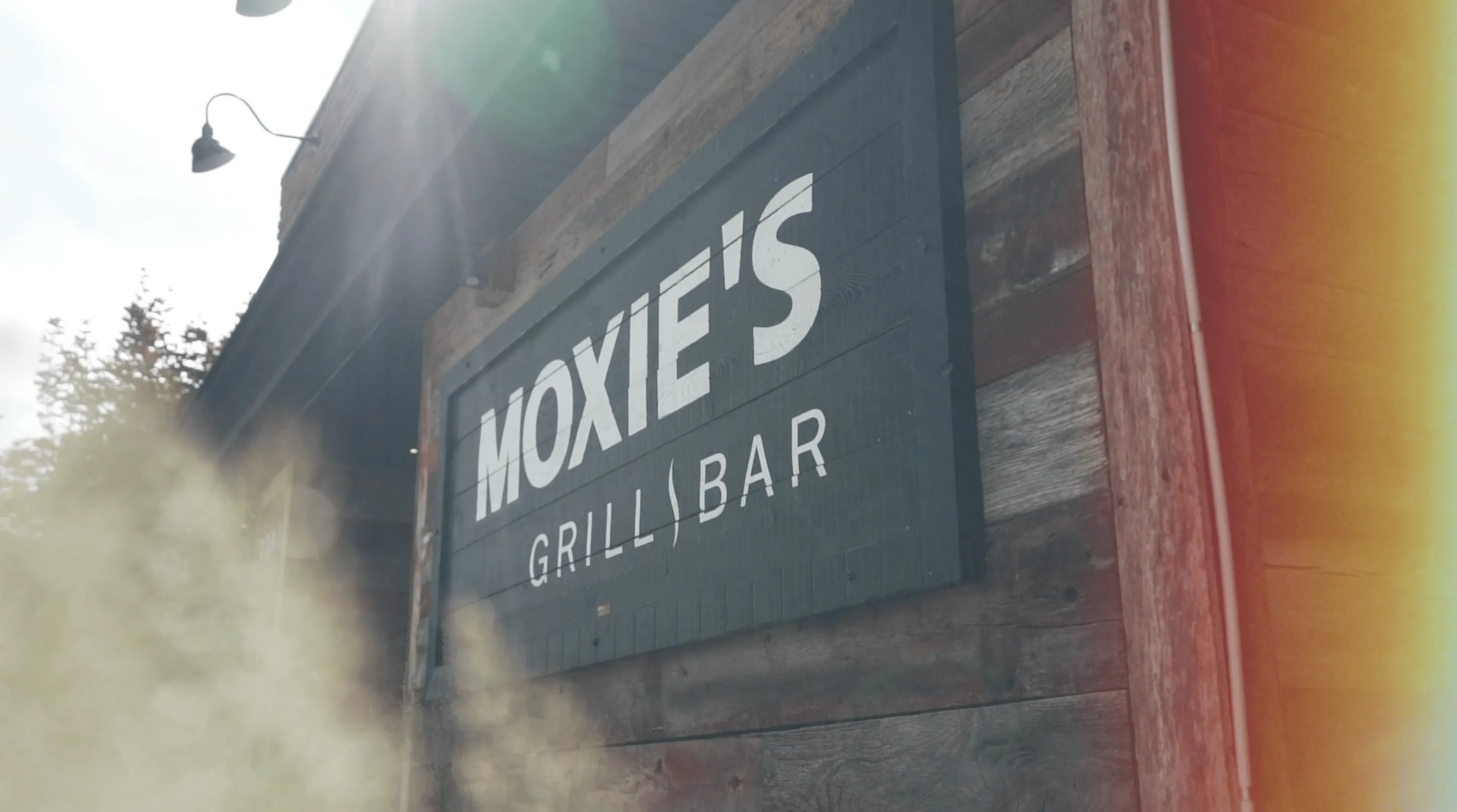 A wooden sign that says Moxie's Grill and Bar