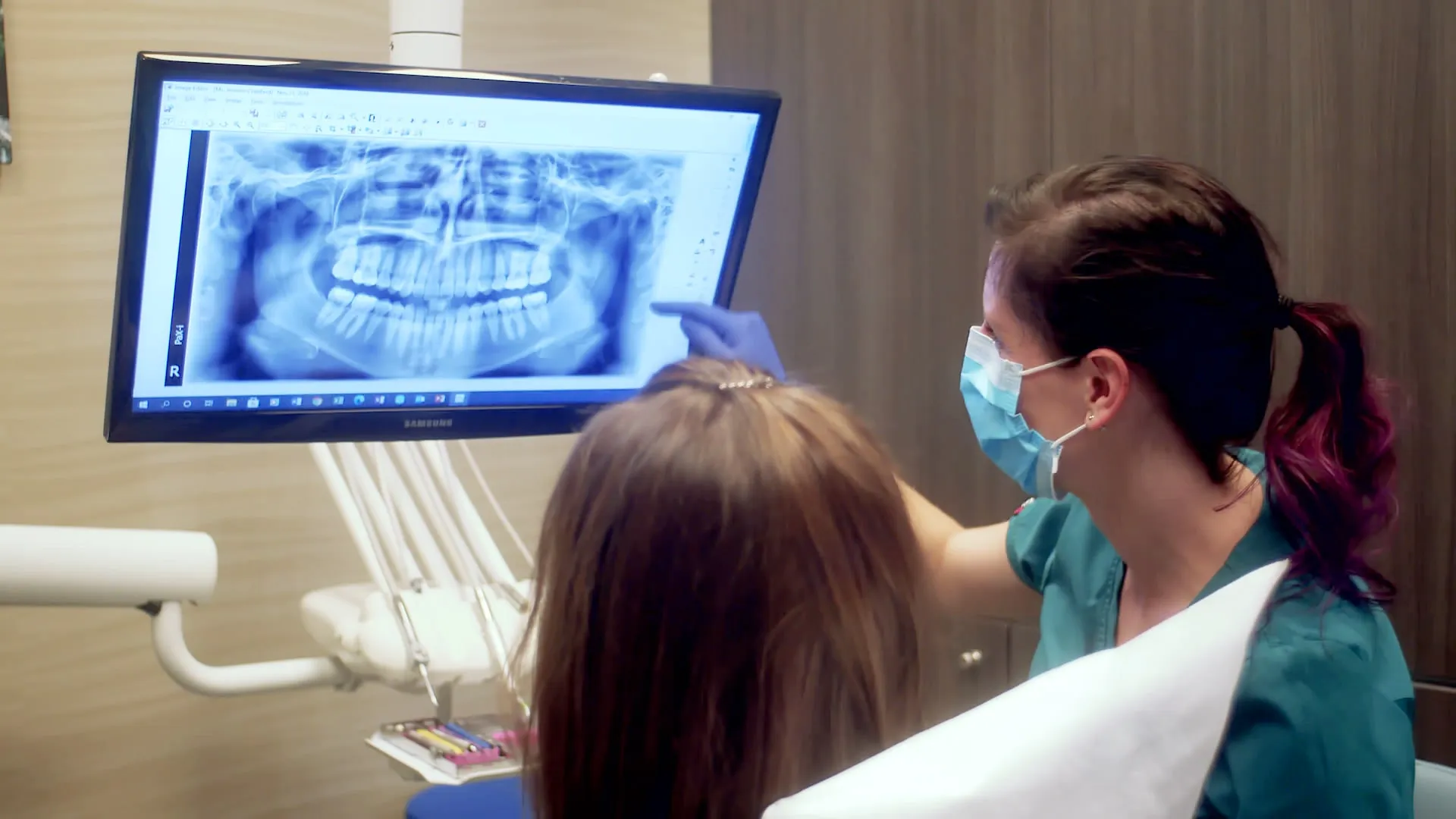 A dentist pointing to an x-ray of a patient's mouth