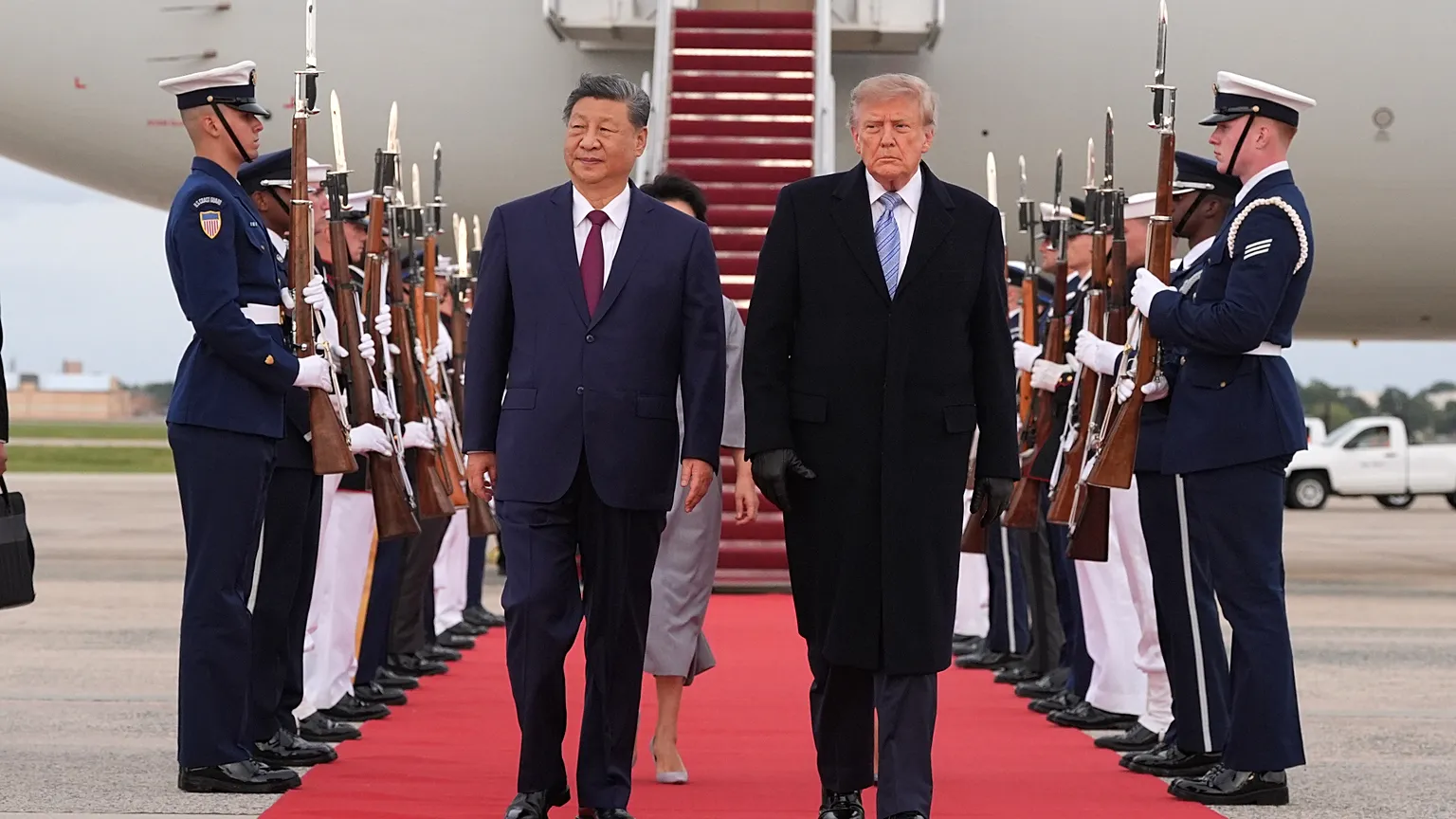 Xi Jinping y Donald Trump caminan juntos entre guardias de honor con fusiles frente a la escalerilla de un avión, en el aeropuerto de Washington.