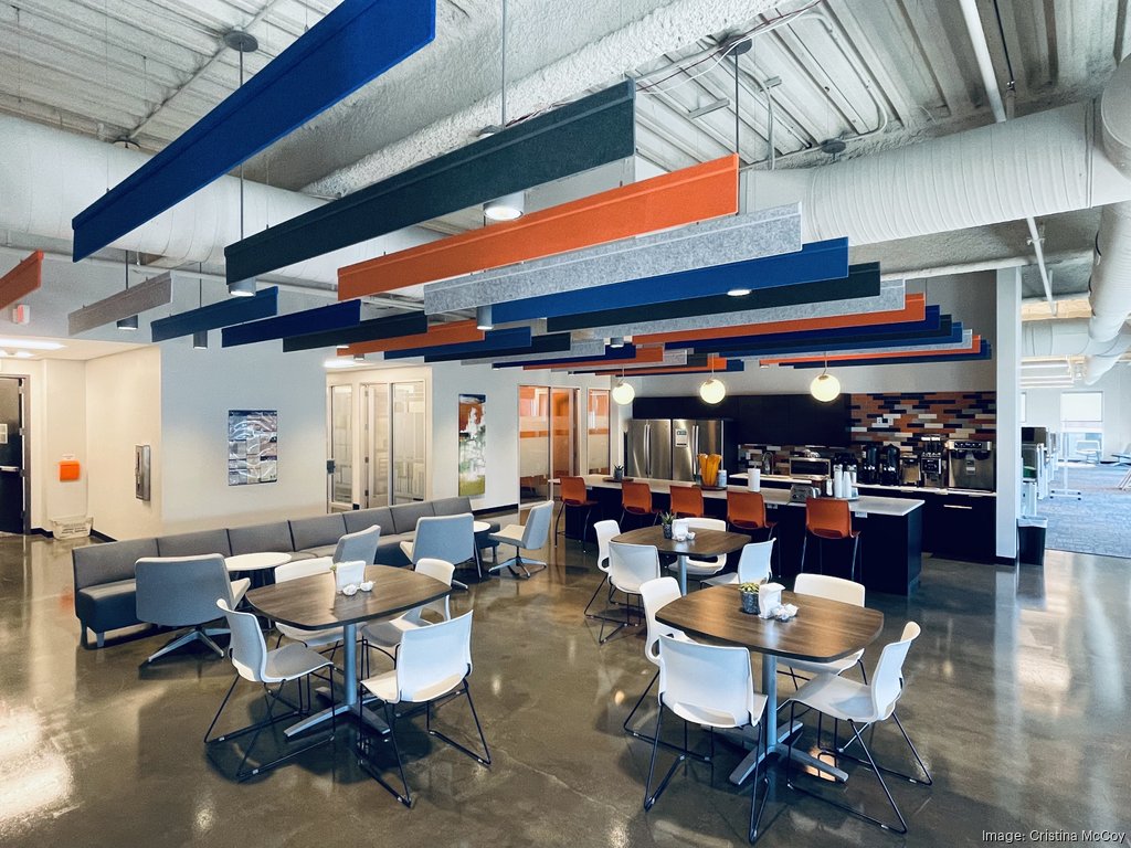 Modern lounge area at Smart Warehousing headquarters showcasing colorful ceiling accents, seating arrangements, and kitchen amenities for employee convenience.