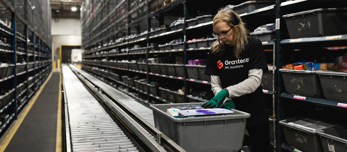 Granterion 3PL Solutions warehouse employee using phone headset, ensuring order accuracy amidst organized shelves, featured in Fulfill.com article about company headquarters and warehouse locations.