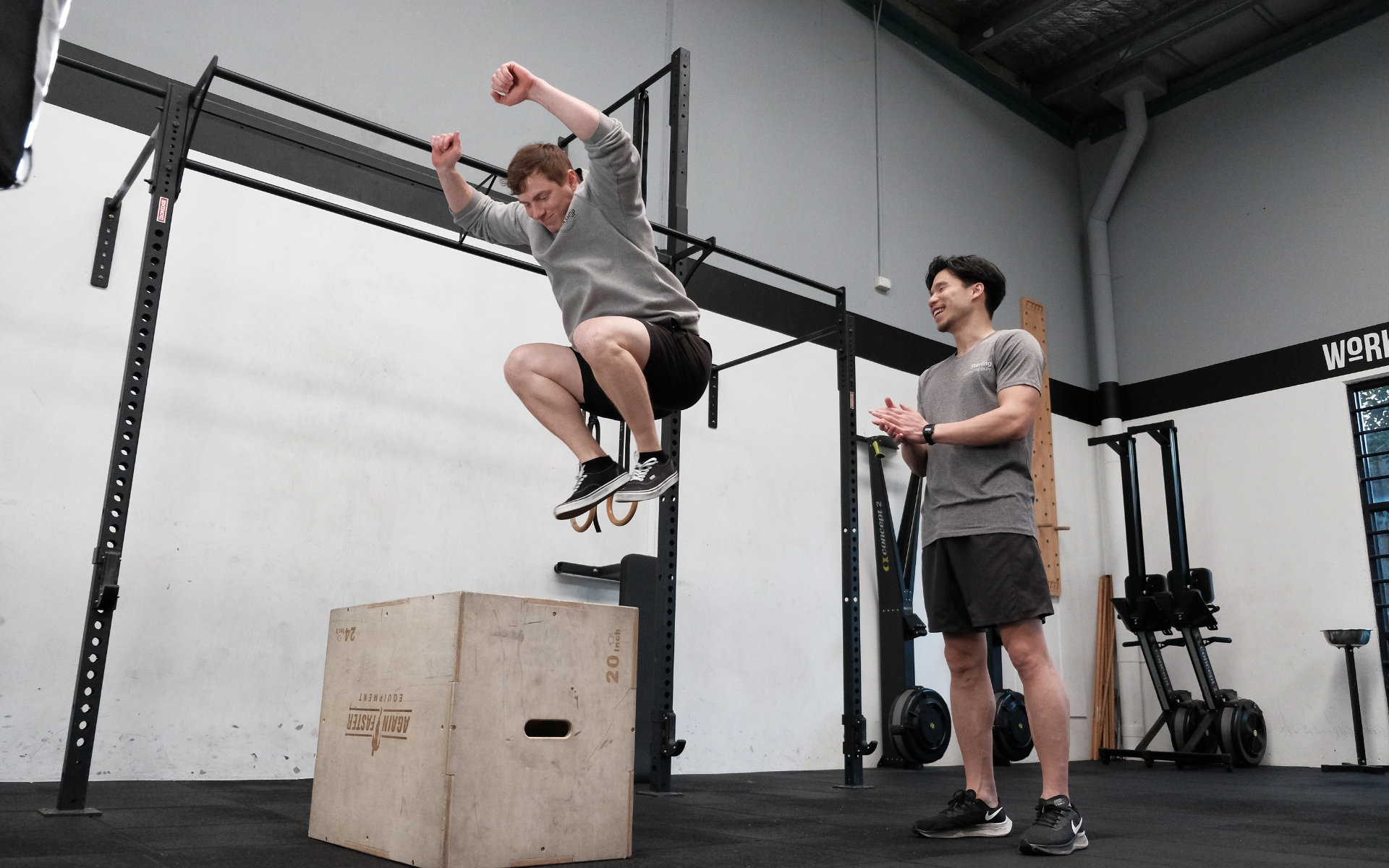 En patient hoppar upp på en träbox medan en fysioterapeut ger honom instruktioner i ett gym.