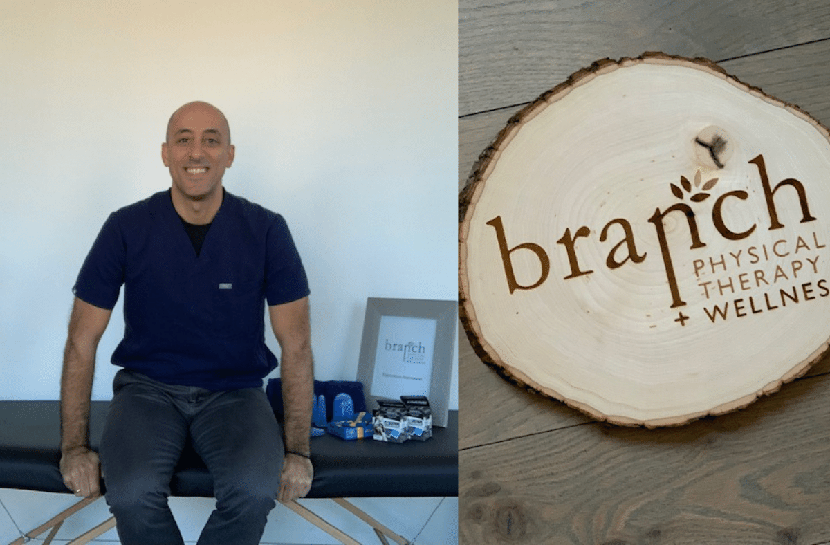 Dr. Marios Christodoulou sits in his clinic next to a wooden Branch Physical Therapy and Wellness logo plaque.
