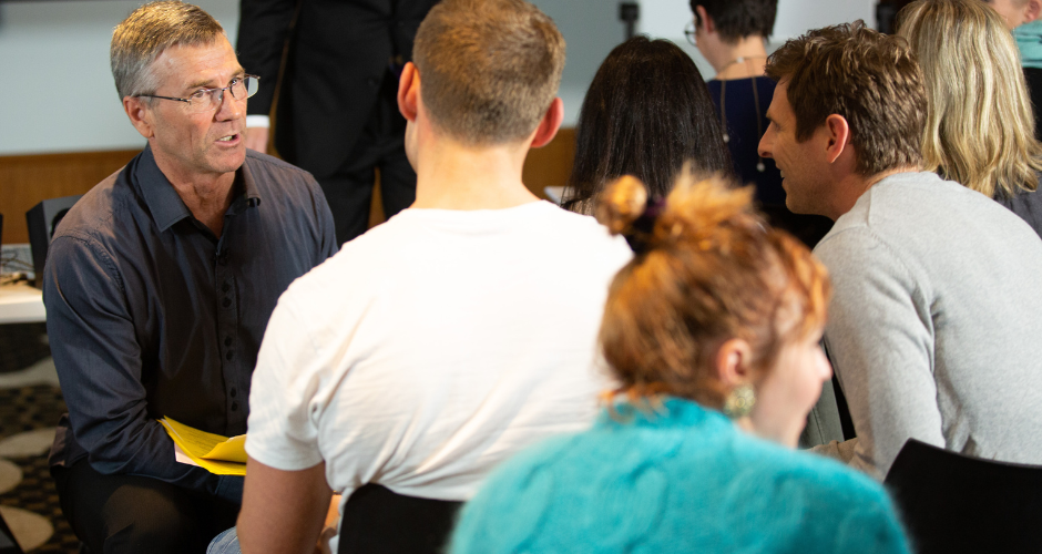 Group of healthcare professionals engaged in a discussion around a table at a professional meeting or workshop.