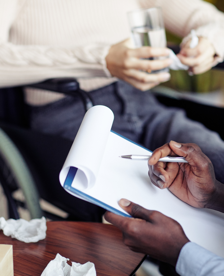 Hands of a clinician writing on a clipboard during a consultation with a patient.