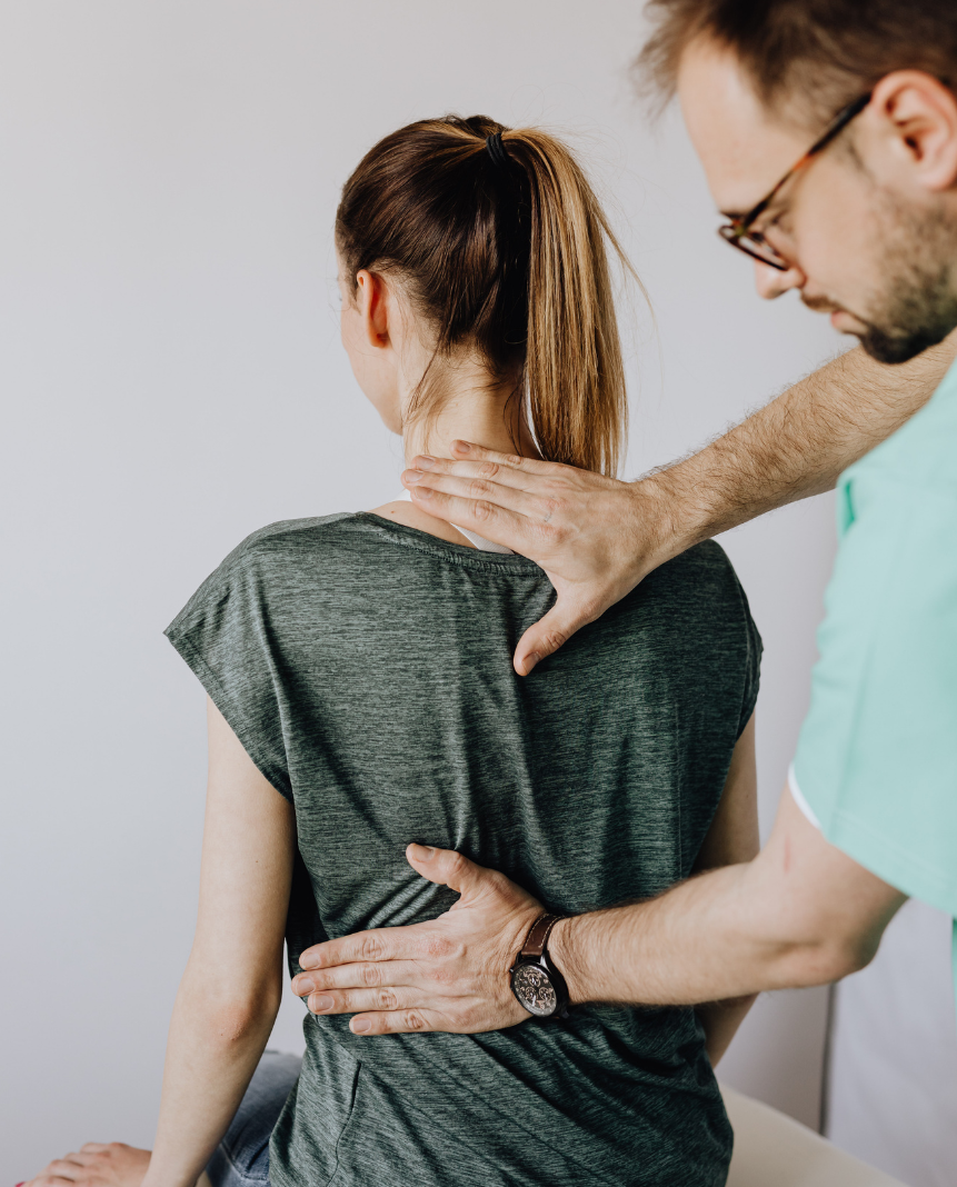 Physiotherapist examining a woman's back and posture during an assessment.