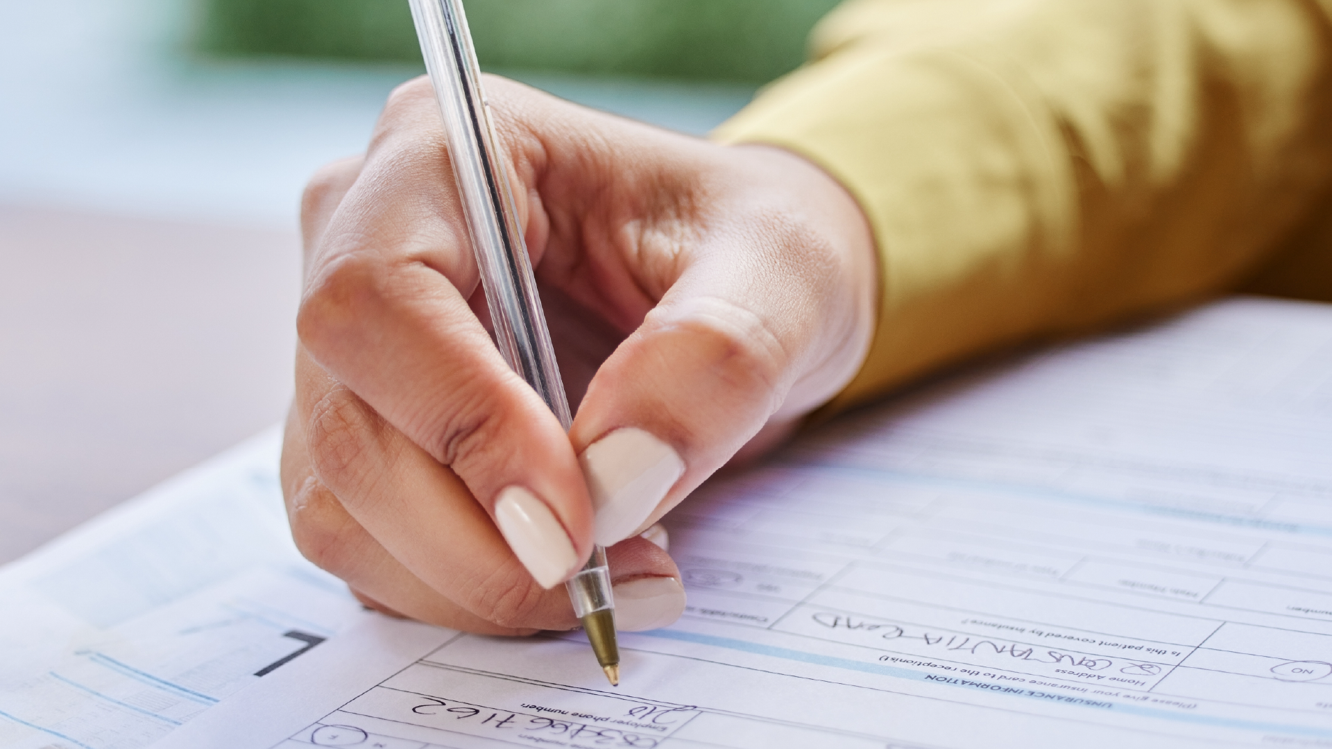 Close-up of a woman's hand filling out a printed questionnaire with a pen