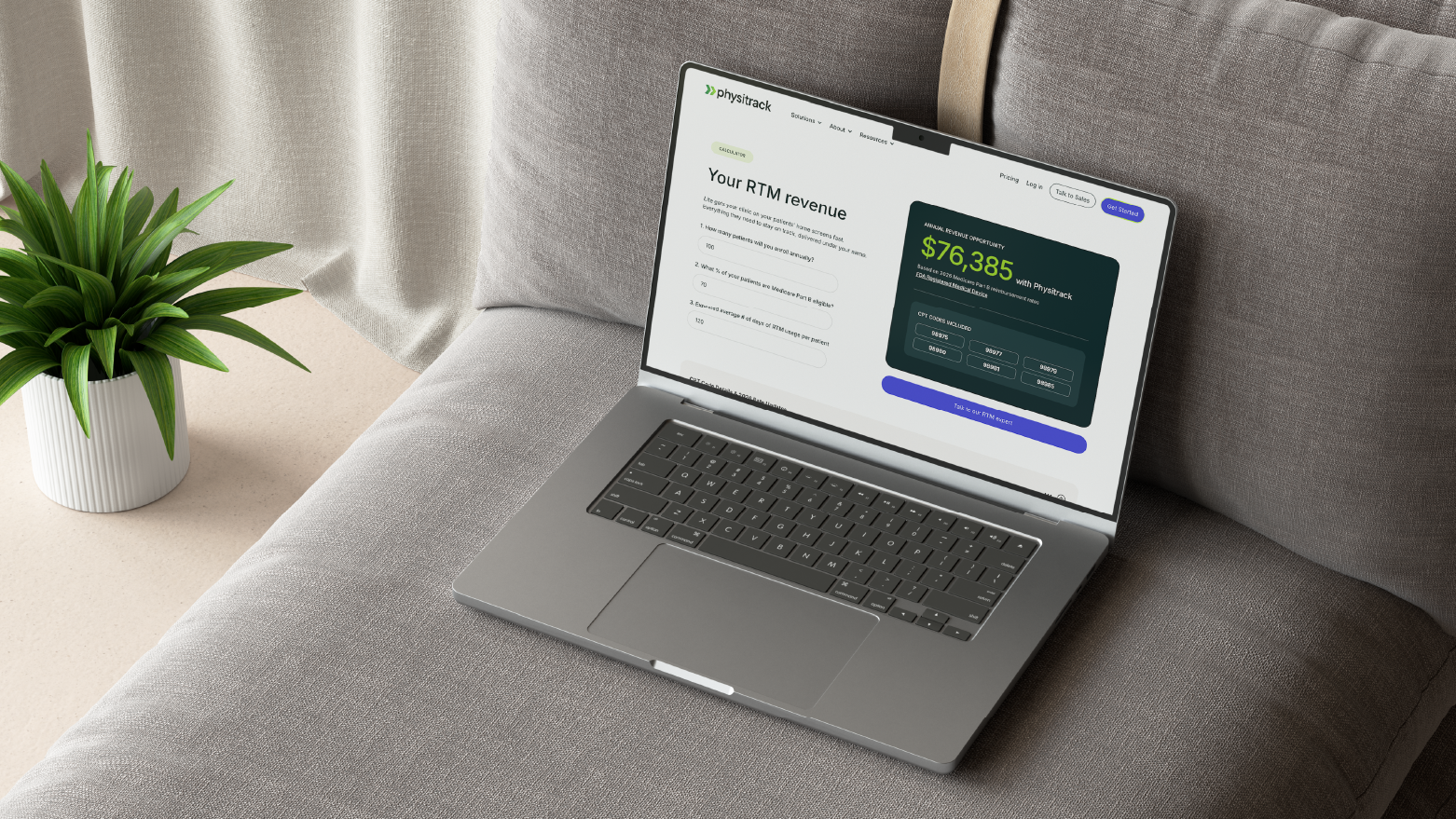 Laptop on a sofa showing a Physitrack RTM revenue dashboard with a $76,385 figure