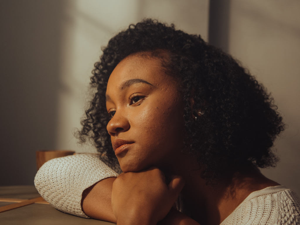 Young woman resting her chin on her hand and gazing pensively toward a window