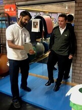 Zwei Männer, die in einem Fitnessstudio in St. George’s neben einem Gymnastikball ein Tablet benutzen